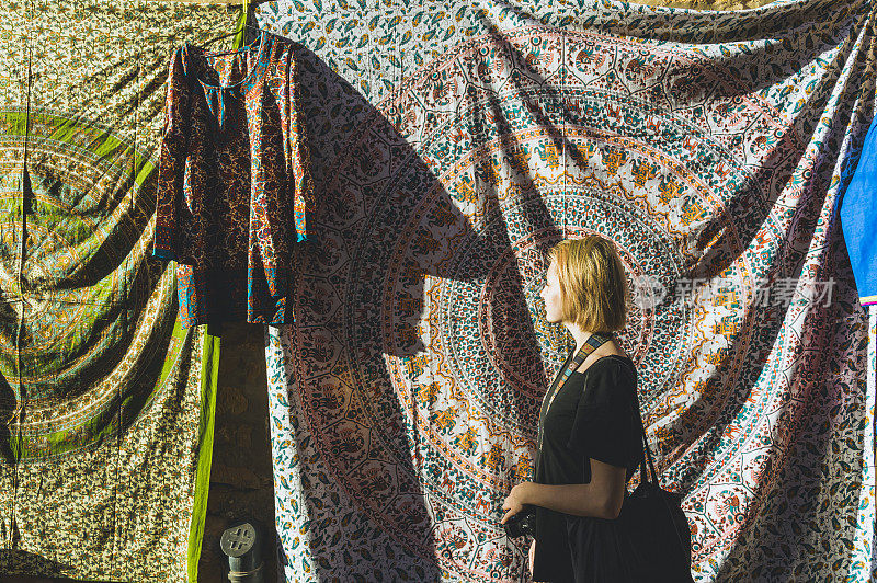 一名年轻女子在露天市场浏览色彩鲜艳的织物