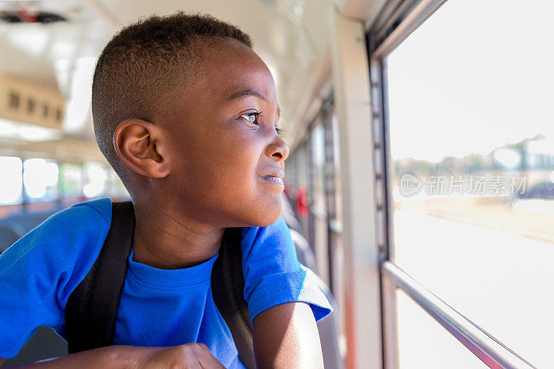 小男孩担心从公共汽车窗口望向学校