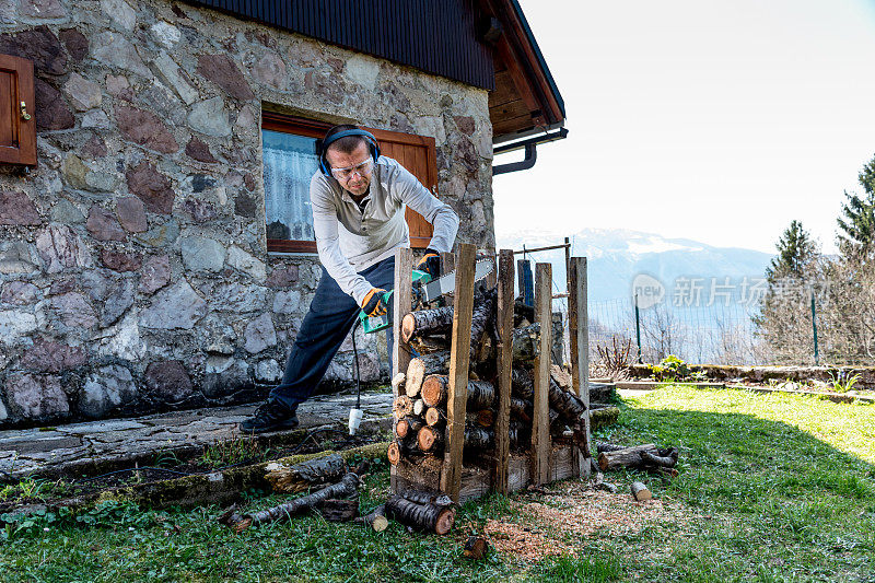 花园里的男人用电锯砍柴