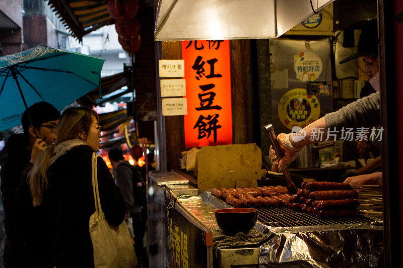 台湾九汾，一对年轻夫妇好奇地看着外卖香肠店。