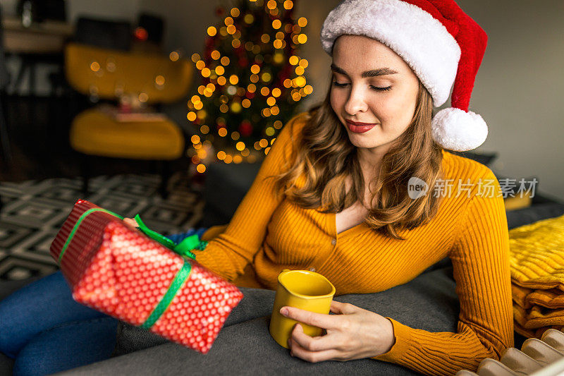 兴奋的漂亮女人拿着圣诞礼物在家喝茶