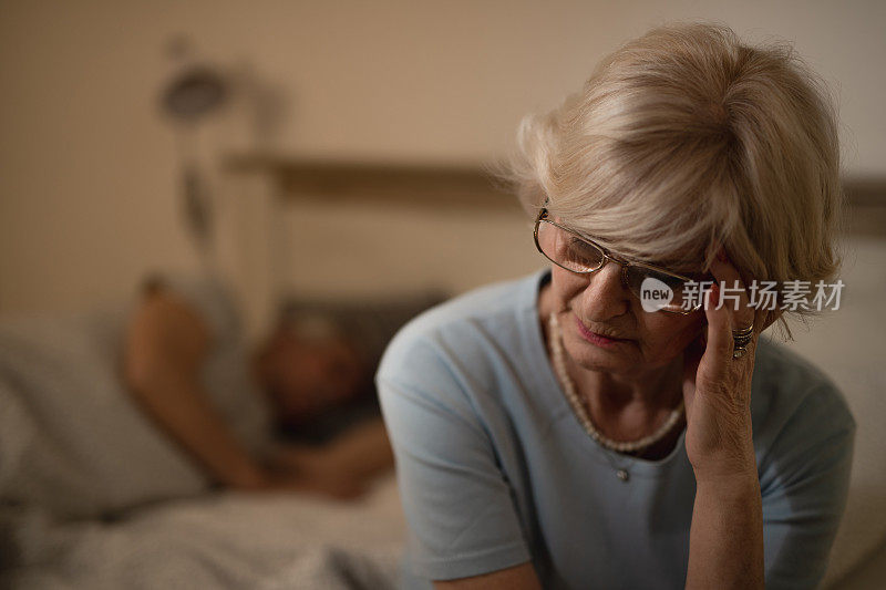 老女人晚上头痛坐在卧室里。