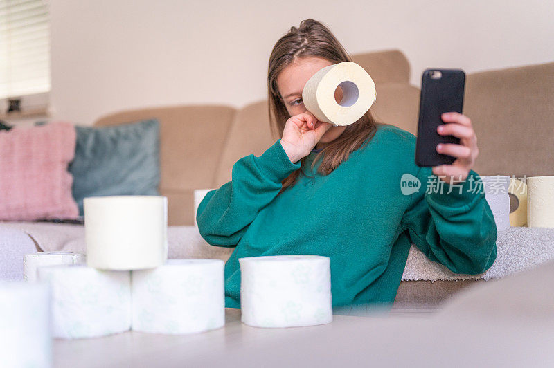 一个女孩在家里看卫生纸，手里拿着手机