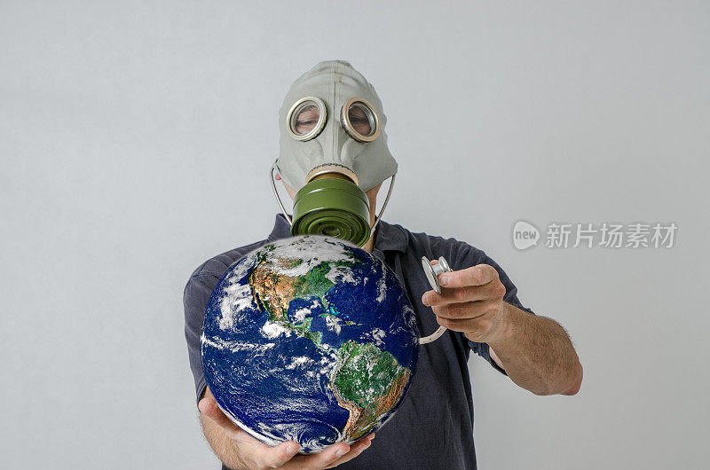 戴着防毒面具的人用听诊器抱着地球