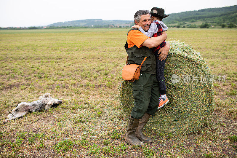 一位快乐的祖父抱着孙子在田野里