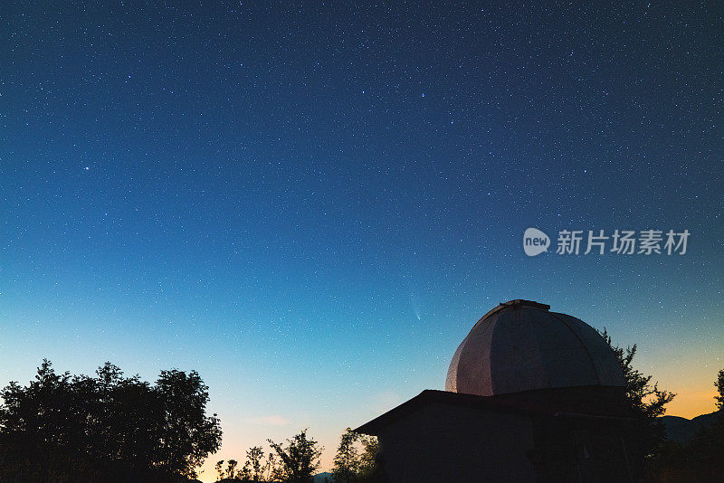 一个夜晚有星星和Neowise彗星在背景的天文台