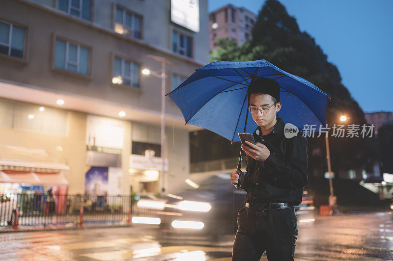 一个十几岁的亚洲华人男孩在雨中走在繁忙的街道上