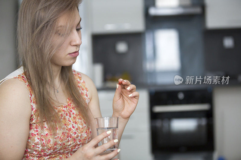 年轻女子拿着药和一杯水