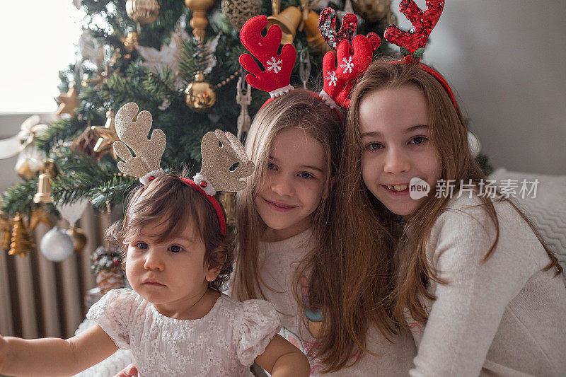 三姐妹在圣诞树下拥抱的肖像