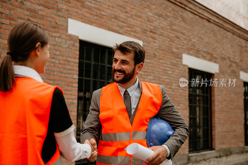 建筑师在建筑工地与建筑工人握手