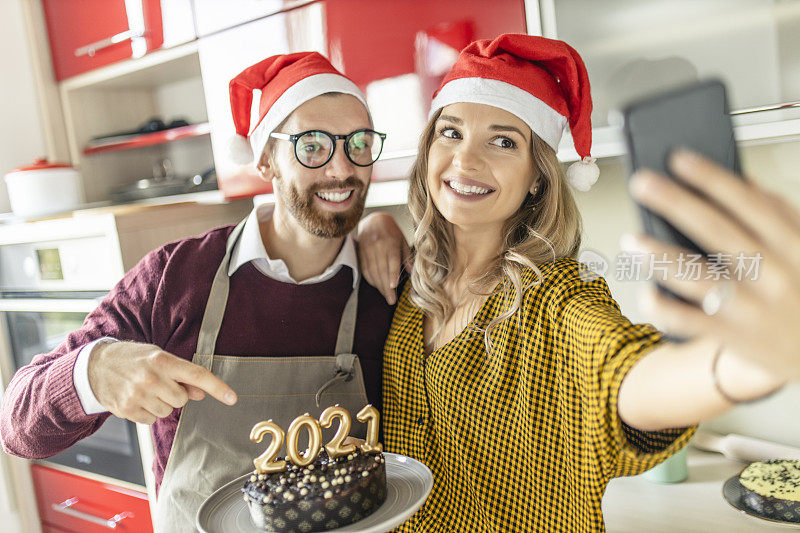 相爱的情侣用巧克力蛋糕自拍，在家里玩，庆祝新年;夫妇与朋友视频电话过年