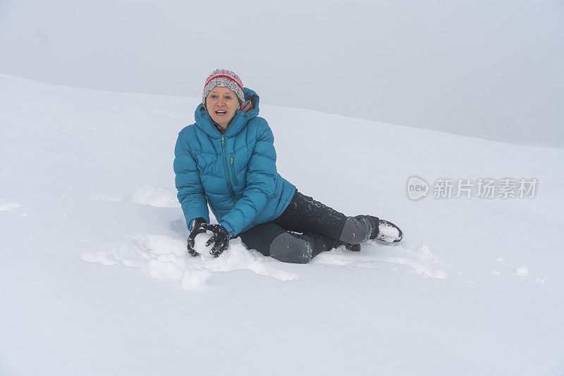 成熟的女人穿着皮大衣在雪地里扔雪球