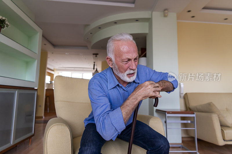 一位拄着拐杖的残疾老人坐在家里，背部疼痛难忍，试图站起来。