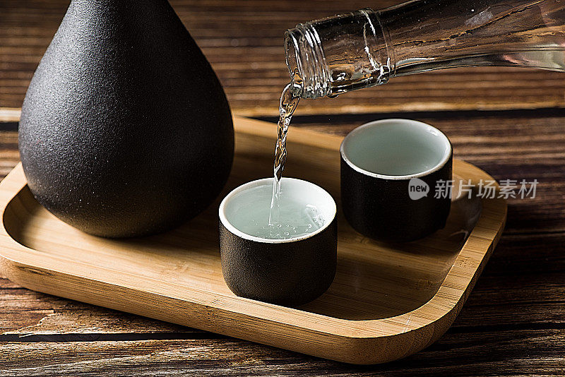 中国白酒，烈酒饮料从一个瓶子倒进一个玻璃杯的木材背景