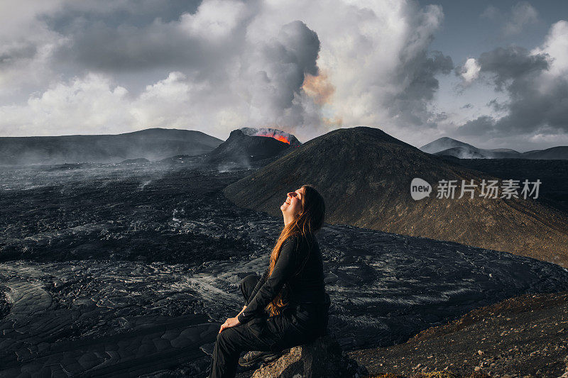 一名年轻的游客正在欣赏冰岛Fagradalsfjall火山喷发时熔化的熔岩的壮观景象