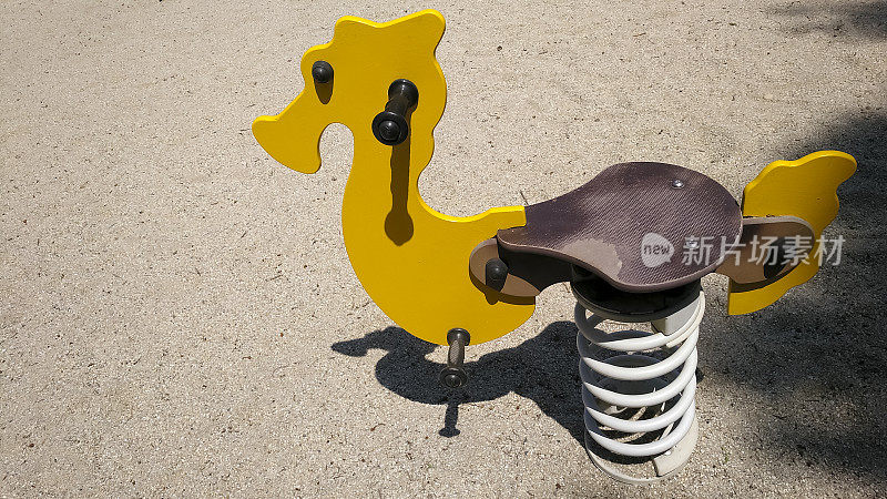 跷跷板呈黄色海马状，是儿童户外游乐场的玩具。