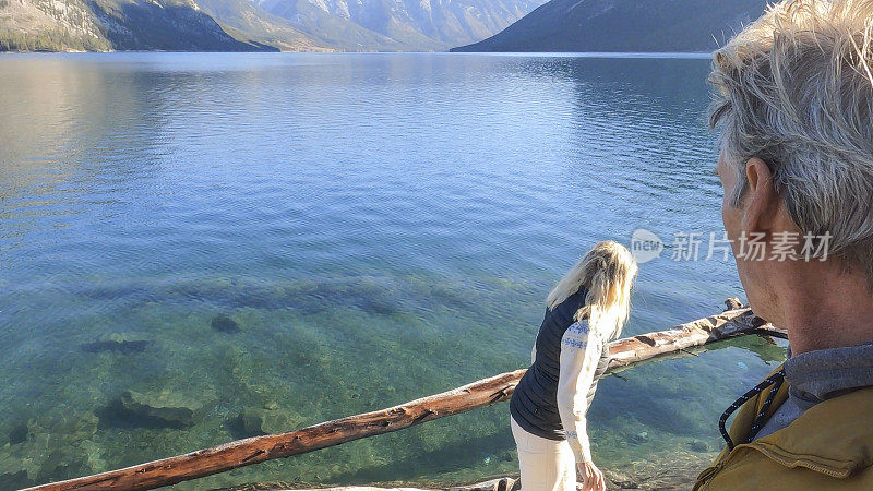 一对夫妇在日出时沿着山湖探索崎岖的海岸线