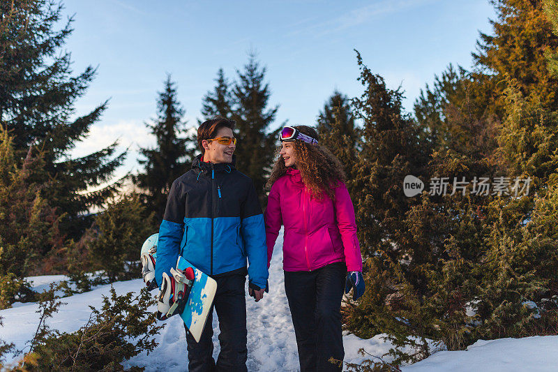 美丽的年轻异性恋夫妇在一个滑雪假期散步在自然而牵手