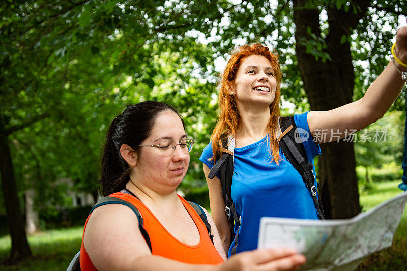 两个年轻的女人一起在大自然中徒步旅行看地图