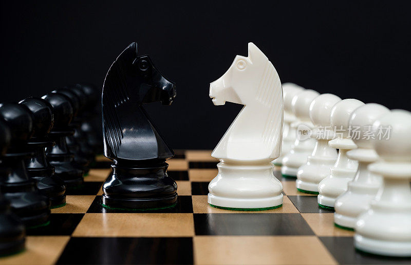 两个国际象棋骑士在黑色背景下战斗
