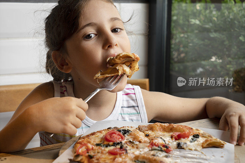 一个小女孩拿着一块美味的披萨
