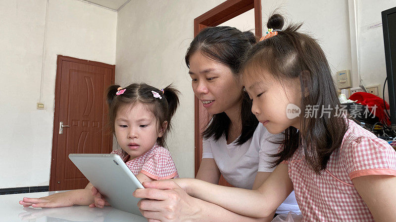 一位亚洲妇女正在使用平板电脑带她的孩子在线学习
