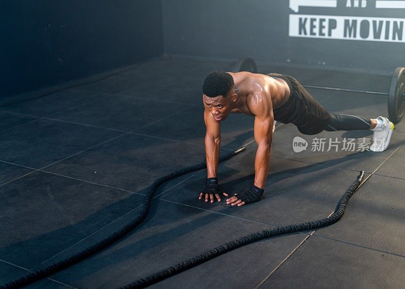 英俊和肌肉发达的非洲黑人男性在健身房战斗绳训练前做热身运动