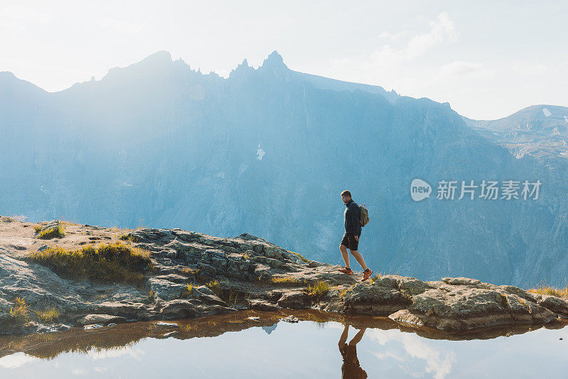 在阳光明媚的秋日，一个背着背包的人在挪威的山上徒步旅行