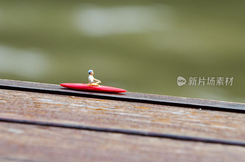小雕像在木制表面上划着红船的特写