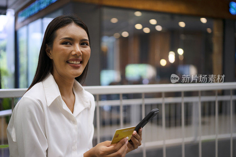 一名年轻女子正在公共场所使用电子银行设备。