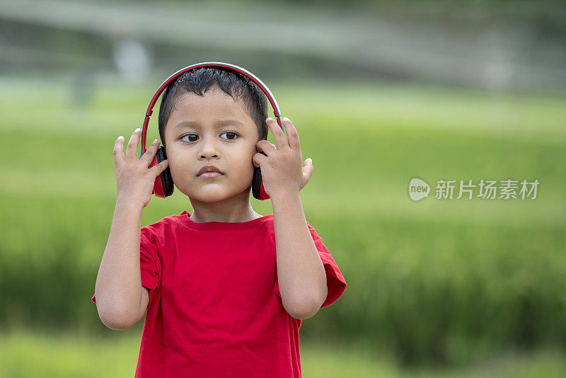 蹒跚学步的男孩用耳机听音乐