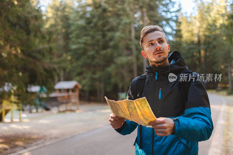 一个年轻的男性徒步旅行者在树林里看地图的腰肖像