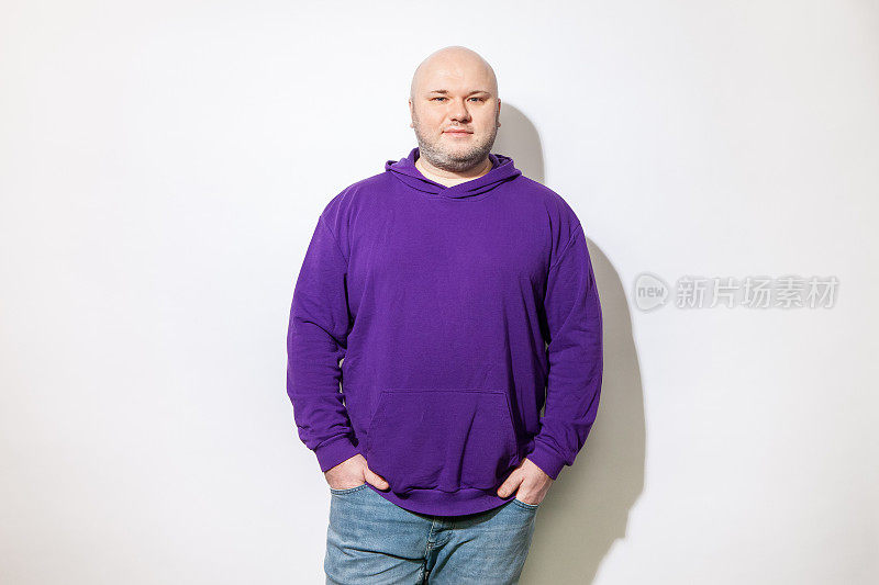 工作室肖像快乐超重中年成年白人男子剃了头，穿着紫色连帽衬衫，对白色背景