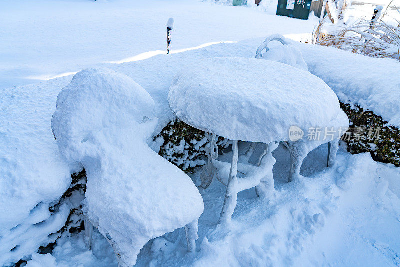 院子里的椅子和桌子被雪覆盖着
