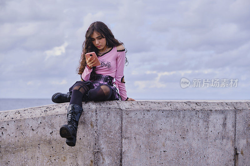 哥特式风格的少女坐在墙上看手机