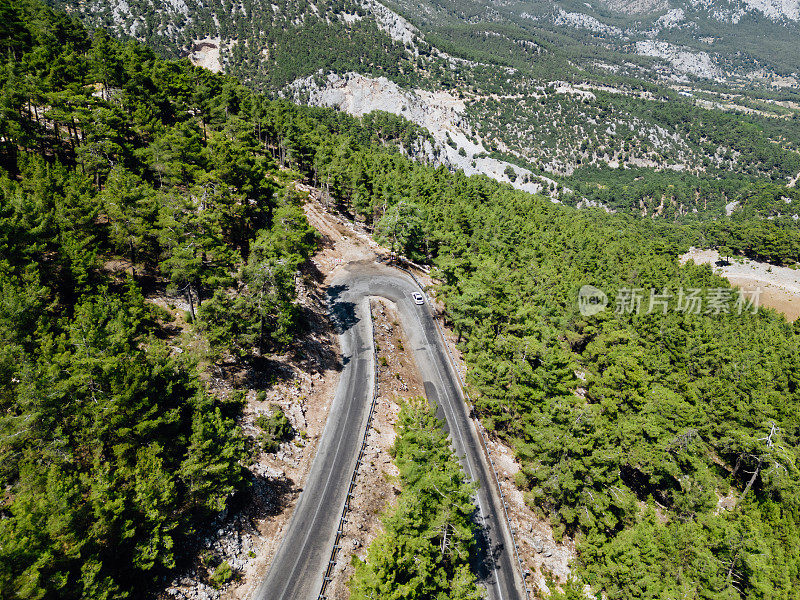 在森林山区的道路上行驶的车辆用无人机拍摄沥青弯道