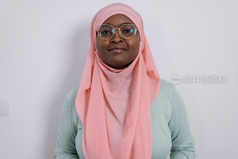 一个年轻的穆斯林妇女在白底上戴着头巾和眼镜拥抱现代的肖像