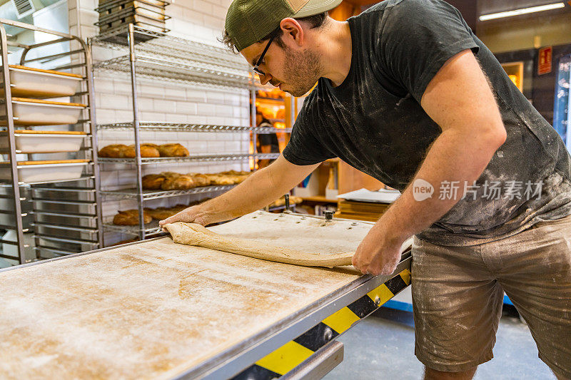 在手工烘焙车间里，把面包放在烤箱前的工人