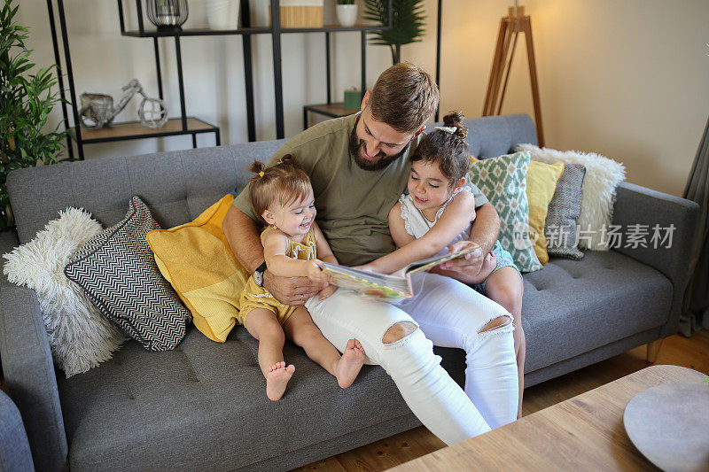 快乐的父亲和女儿在新家里看相册。库存图片