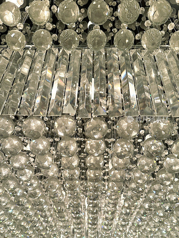 水晶吊灯的全帧图像与闪闪发光的矩形和球形切割玻璃，从下面看，墙纸背景
