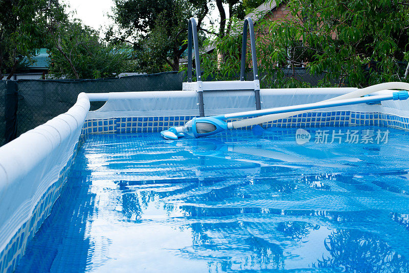 游泳池带真空吸尘器清洁工具。太阳能薄膜覆盖着游泳池。