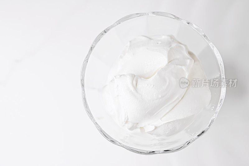 白色打发的甜点奶油装在玻璃碗里，奶油般的质感