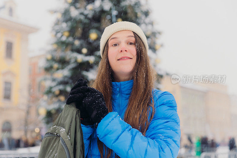 快乐的女人背着背包，在克拉科夫思考下雪的圣诞节