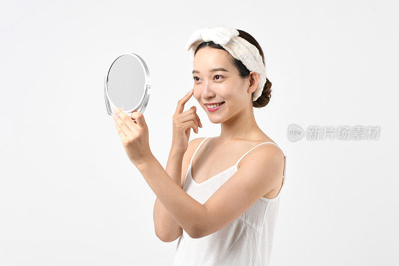年轻美丽的亚洲女人在照镜子时做皮肤护理