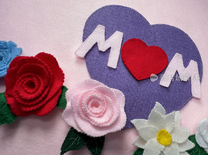手工制作的母亲节卡片，用毛毡，紫色的心，底部有“妈妈”这个词，粉红色的背景上有鲜花和玫瑰