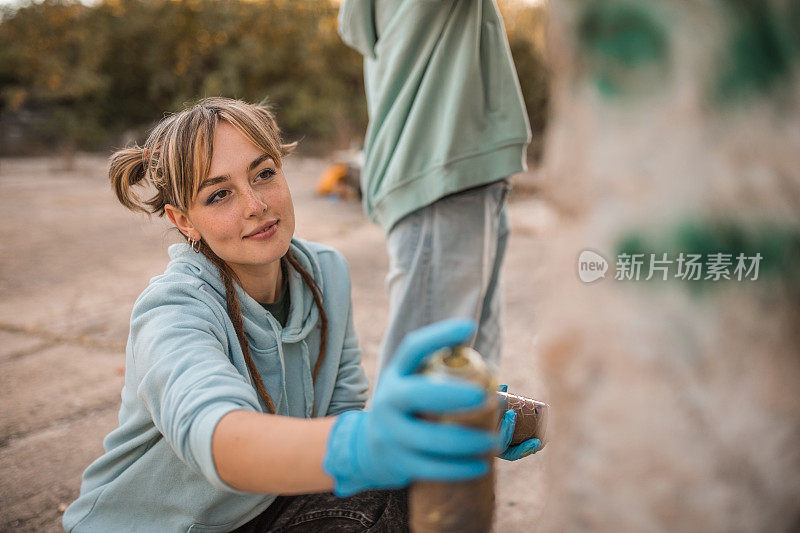 可爱的女人手里拿着喷漆，和朋友一起涂鸦