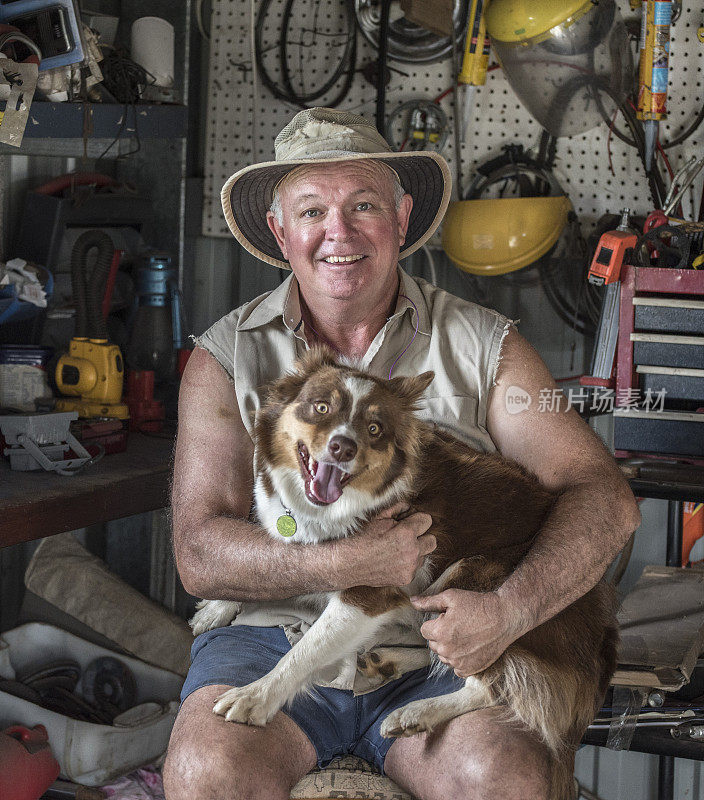 一名澳大利亚男子在他的牛棚里快乐地抱着他的牧牛狗。