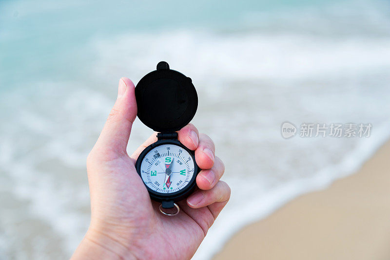 在海滩上，一个手持指南针的男人