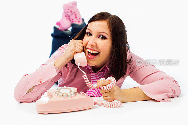 年轻的女孩在用粉红色的手机说话，面带微笑