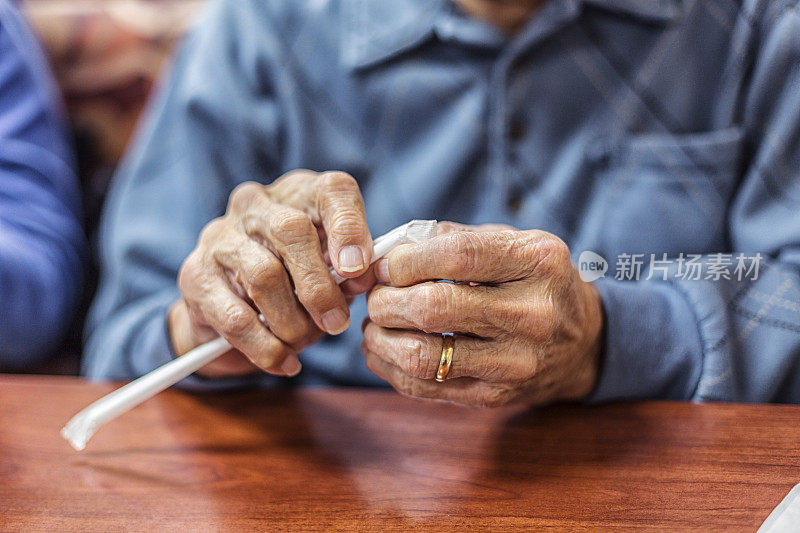 老人双手去除饮用草纸包装袋